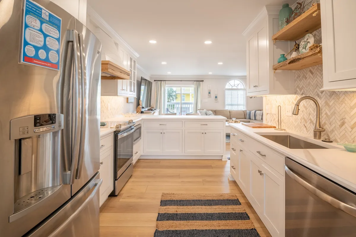An open-layout kitchen filled with natural light, featuring stainless steel appliances and decorative shelving. The scene feels inviting and functional, perfect for group cooking or casual family gatherings.