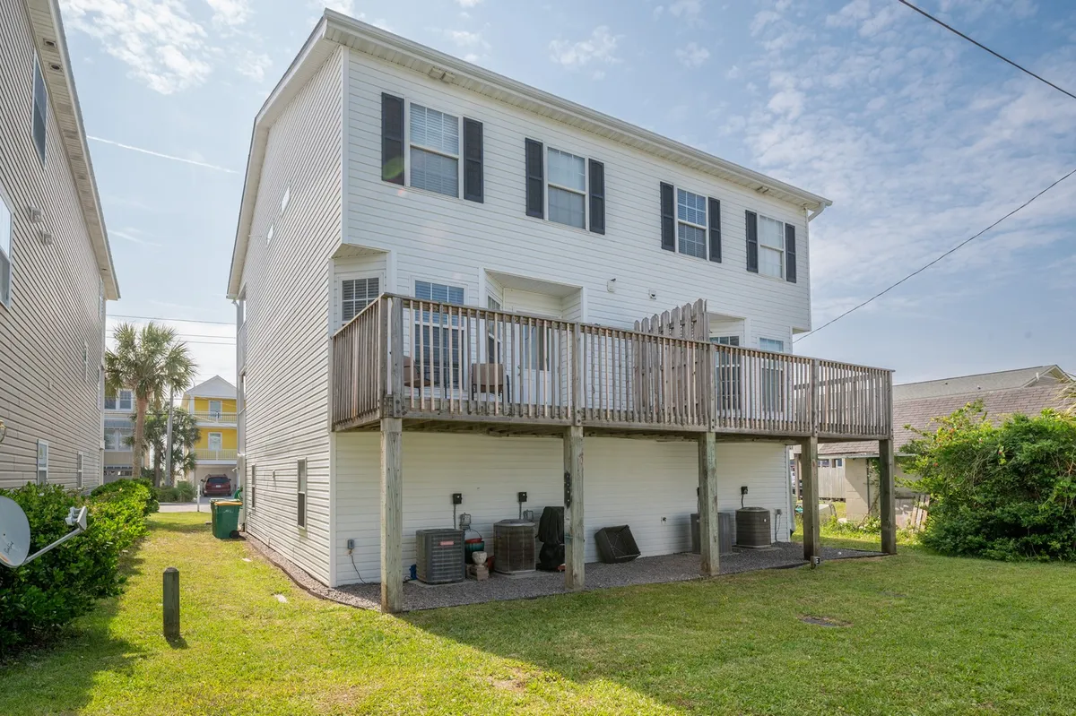 A sunny deck attached to the home, bordered by windows and overlooking a green lawn. The space is set up for outdoor dining or relaxation, seamlessly connecting indoor living to the backyard.